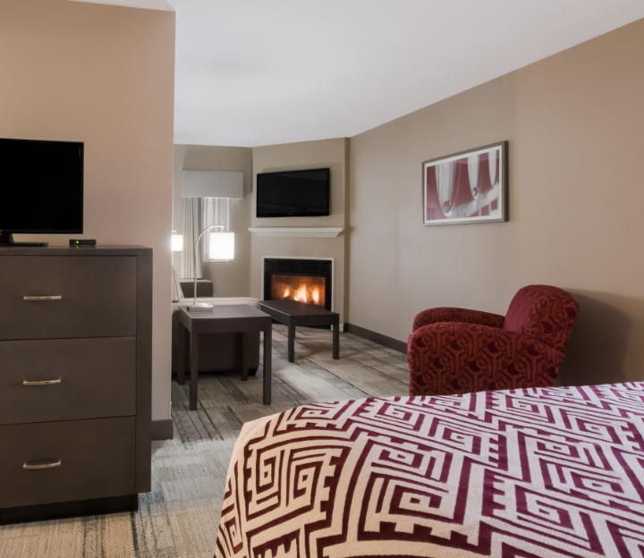 Best Western Niagara-on-the-Lake Queen suite with one red patterned armchair and a fireplace.