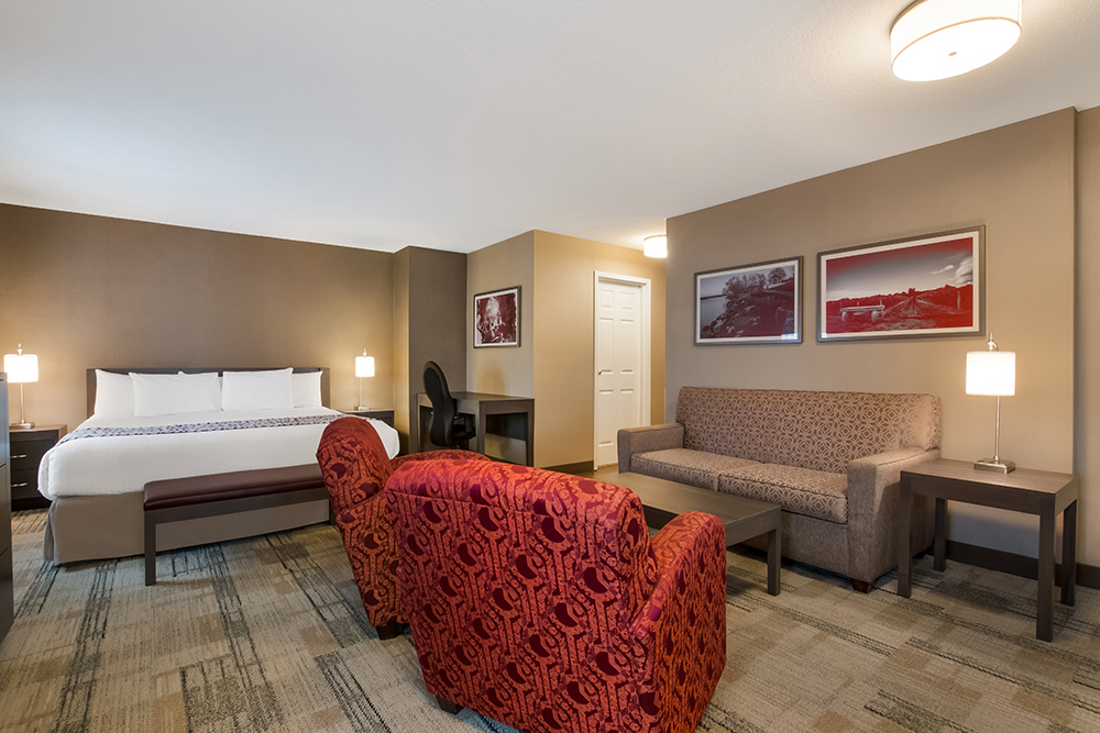 Best Western King suite with two red patterned armchairs and a fireplace.